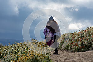 Latina Mother and Daughter in front of desert California Poppy field on path with orange and yellow flowers