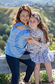 Latina Mother and Daughter Smiling and laughing on a hill in front of yellow flowers