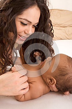 Latina mother playing with her baby boy son on bed