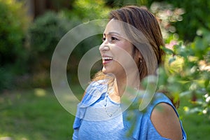 Latina Mother Smiling in Back Yard in front of red leaved bush