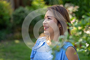 Latina Mother Smiling in Back Yard in front of red leaved bush