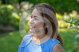 Latina Mother Smiling in Back Yard in front of red leaved bush