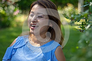 Latina Mother Smiling in Back Yard in front of red leaved bush