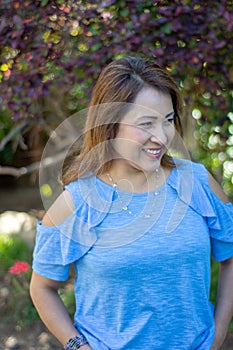 Latina Mother Smiling in Back Yard in front of red leaved bush