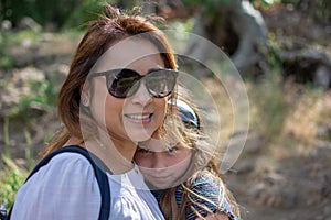 Latina Woman and daughter smiling together while standing in front of woods at a park photo