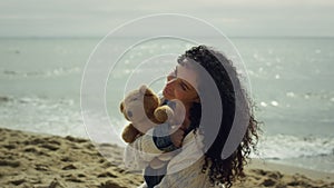 Latina woman posing sea beach. Gorgeous lady modeling holding teddy bear outside