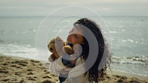 Latina woman posing sea beach. Gorgeous lady modeling holding teddy bear outside