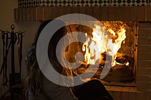 latina woman sitting in front of the fireplace in cold winter