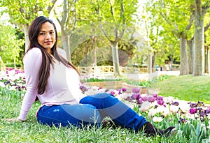Latina woman sitting in a park meadow with tulips