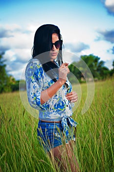 Latina woman with sunglasses and shorts walking through the field in cuba