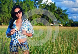 Latina woman with sunglasses and shorts walking through the field in cuba