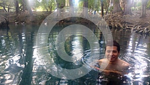 Latino adult man swims in crystal clear spring water of the Media Luna natural lagoon in the municipality photo