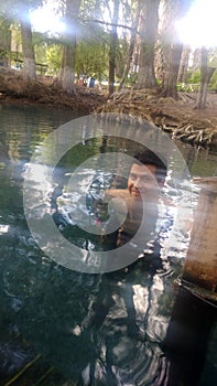 Latino adult man swims in crystal clear spring water of the Media Luna natural lagoon in the municipality photo