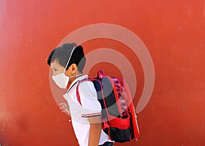 Latino boy with uniform shirt, backpack and mask back to school happy and excited about the new normal for the Covid-19 pandemic