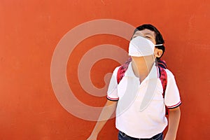 Latino boy with uniform shirt, backpack and mask back to school happy and excited about the new normal for the Covid-19 pandemic