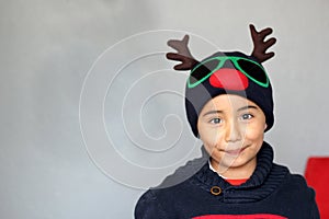 Latino boy 7 years old with Christmas hat with reindeer ears and sweater. Christmas decoration