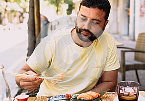 Latino boy in yellow t-shirt eating japanese food