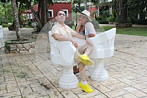 Couple sitting on a bench confidant chairs in Merida in Yucatan Mexico show their love with flirtatious looks and kisses photo