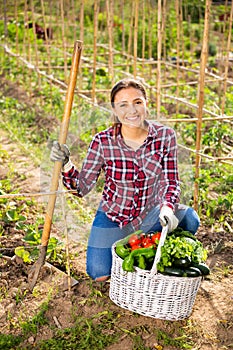 Latino girl farmer with basket of vegetables in the garden