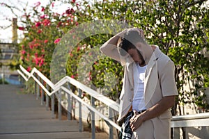 Latino and Hispanic boy, young and nonconformist, rebellious, with beige jacket and pants, with his hand on his head sad and alone