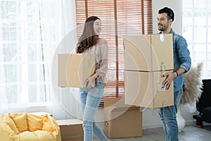 Latino man with beard and Asian woman couple help to carry packed cardboard boxes into their new home where they were moving in