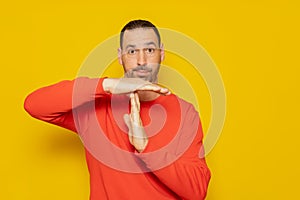 Latino man with a beard in a red sweatshirt making the time-out gesture, he needs a break from the pace of life demanded