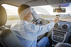 Latino man using a mobile phone inside his car