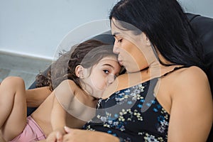 Latino mother kisses baby`s forehead while breastfeeding