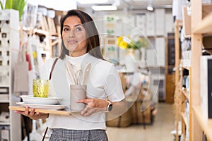 Latino woman holding purchases and walking in household goods store