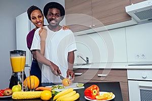 Latino woman and man working at juice bar and cutting fruits, making fresh smoothies from bananas,orange and melon. she