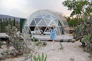 Latino woman outside a geodesic glamping tent with a roof and transparent windows to view the sky and stars