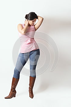 Latino woman with a pink t-shirt and cowboy boots posing in studio with a cute pose