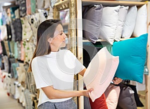 Latino woman purchaser holding variety pillows in textile shop