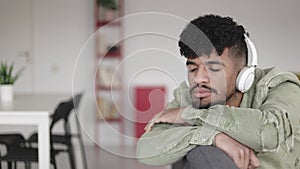 Latino young man with closed eyes relaxing at home listening to music