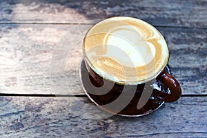 Latte art on a cappucinno , on wooden table photo
