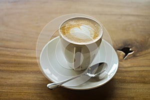 Latte art on a cappucinno , on wooden table photo