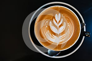 Latte art coffee in black cup on  black table