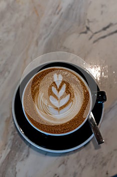 Latte art coffee in black cup on marble table