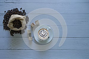 Latte art coffee in a coffee cup and coffee beans isolated with sack bag and coffee wooden dice on top left corner