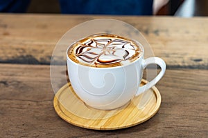 Latte art coffee cup with wooden saucer