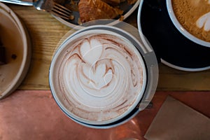 Latte art and Coffee Cups with Cinnamon on the Table, accompanied by Saucer, Spoon, and Sugar a delightful morning beverage scene