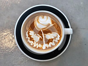 Latte art coffee Flower shape in black and white cup on the cement background