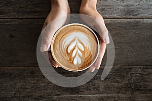 Latte art coffee with heart tree  shape in coffee cup holding by hand