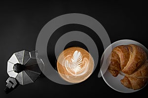 Latte art coffee in a white cup Two sides with Italian Moka pots, coffee and croissants, top view, black background, empty space,