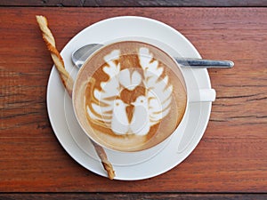 Latte art coffee on the wooden desk.