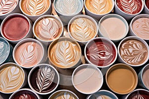 latte art patterns on multiple coffee cups lined up
