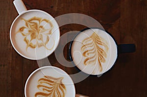 Latte art - three cups on coffee on dark wooden background