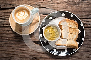 Latte and cake on a wooden table in the cafe.