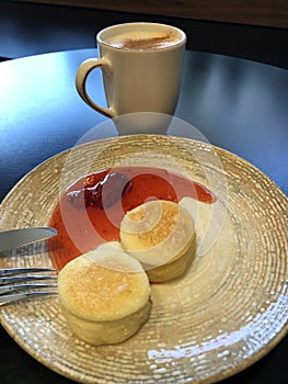 Latte with cinnamon and cheesecakes with strawberry jam