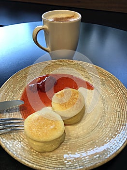 Latte with cinnamon and cheesecakes with strawberry jam